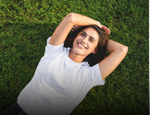 Une femme allong&eacute;e dans l&rsquo;herbe, affichant une peau saine et &eacute;clatante gr&acirc;ce &agrave; la Routine Glow de Kneipp.